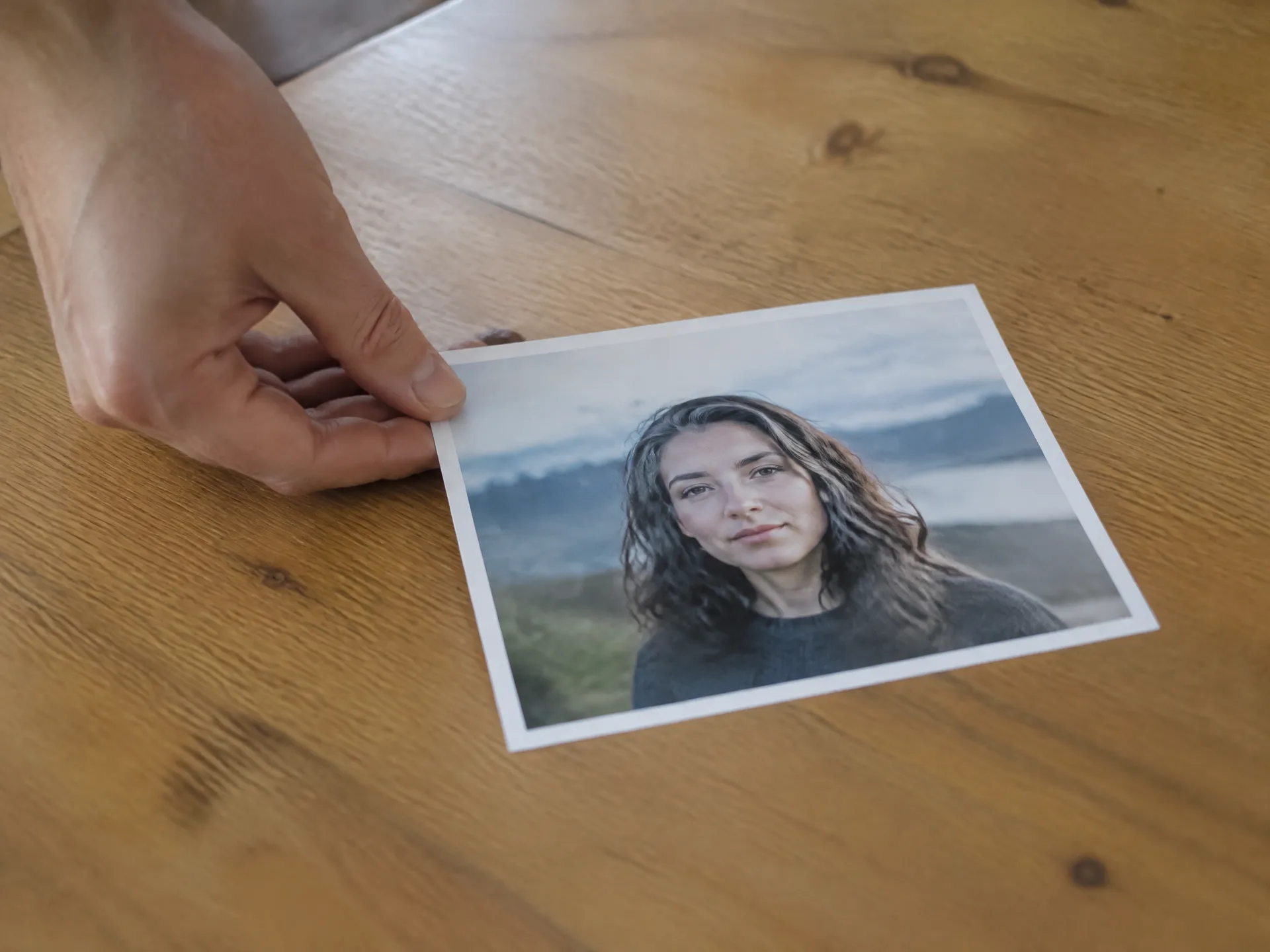 Hand placing a printed portrait photo on a wooden table