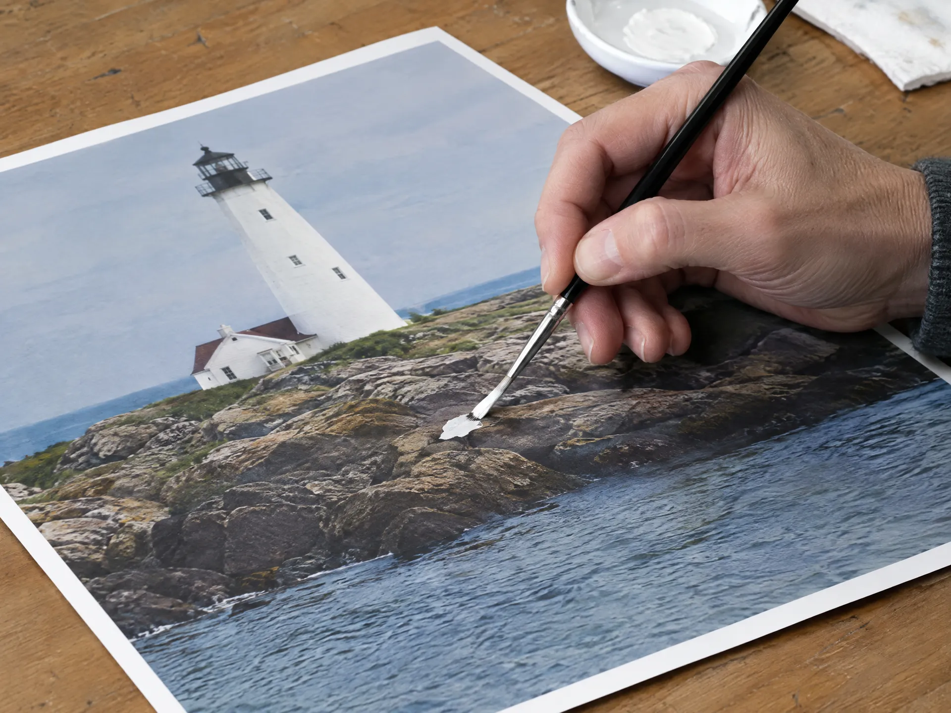 Hand retouching a printed photo with a paintbrush and white paint