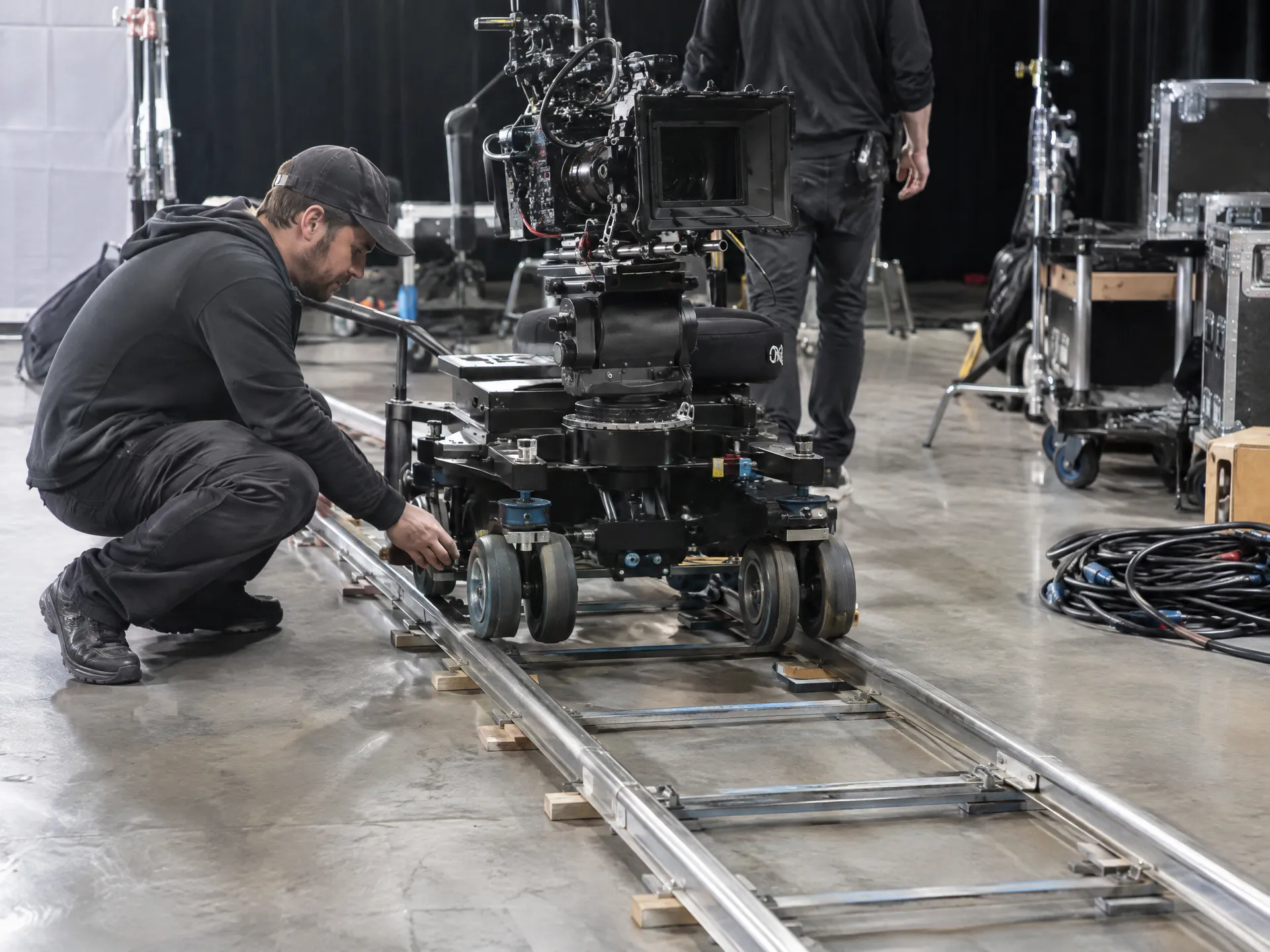 Film dolly track and camera rig with a crew member adjusting it