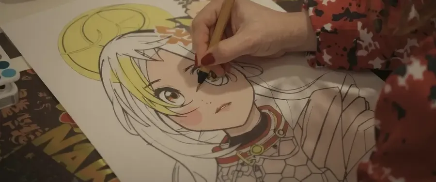 A hand coloring the eye of a manga-style character drawing on paper