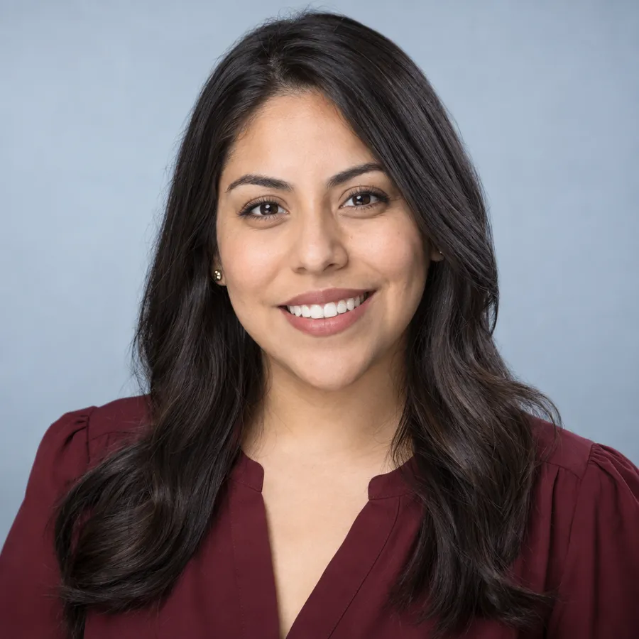 Headshot of a woman in a burgundy blouse on a pale blue-grey studio background