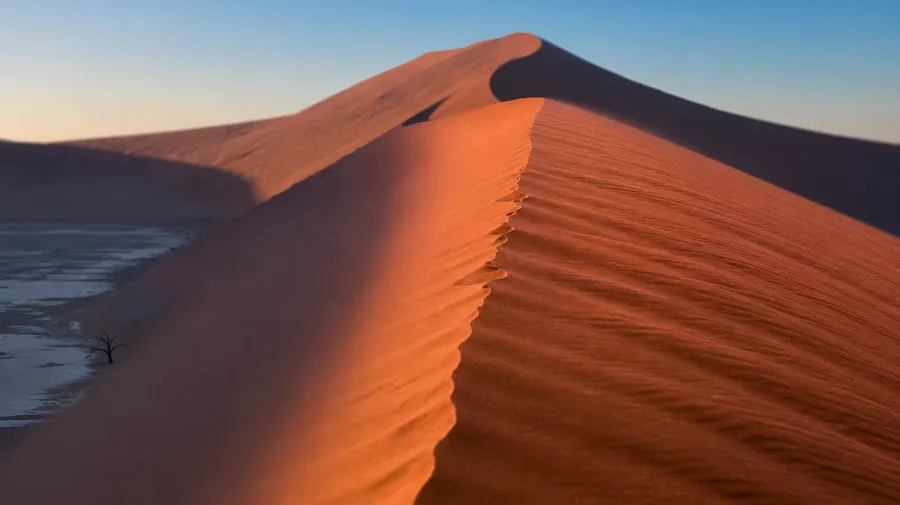 Namib red sand dune ridgeline at Sossusvlei in first light, AI-generated desert images stock photo.