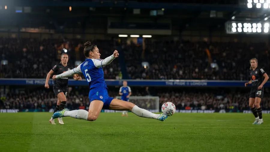 AI stock football image: women's quarter-final under floodlights with defender mid-clearance
