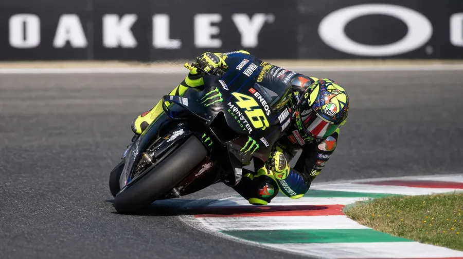 AI-generated racing photo: MotoGP rider knee-down at Mugello, leather puck sliding on the apex line.
