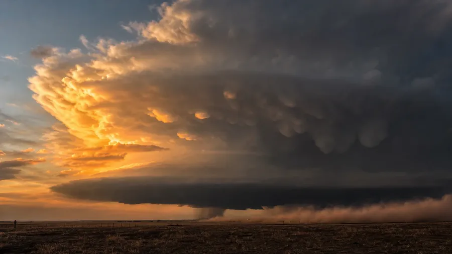 AI sky picture of a massive cumulonimbus thunderhead building over a Midwestern prairie at golden hour with anvil top.