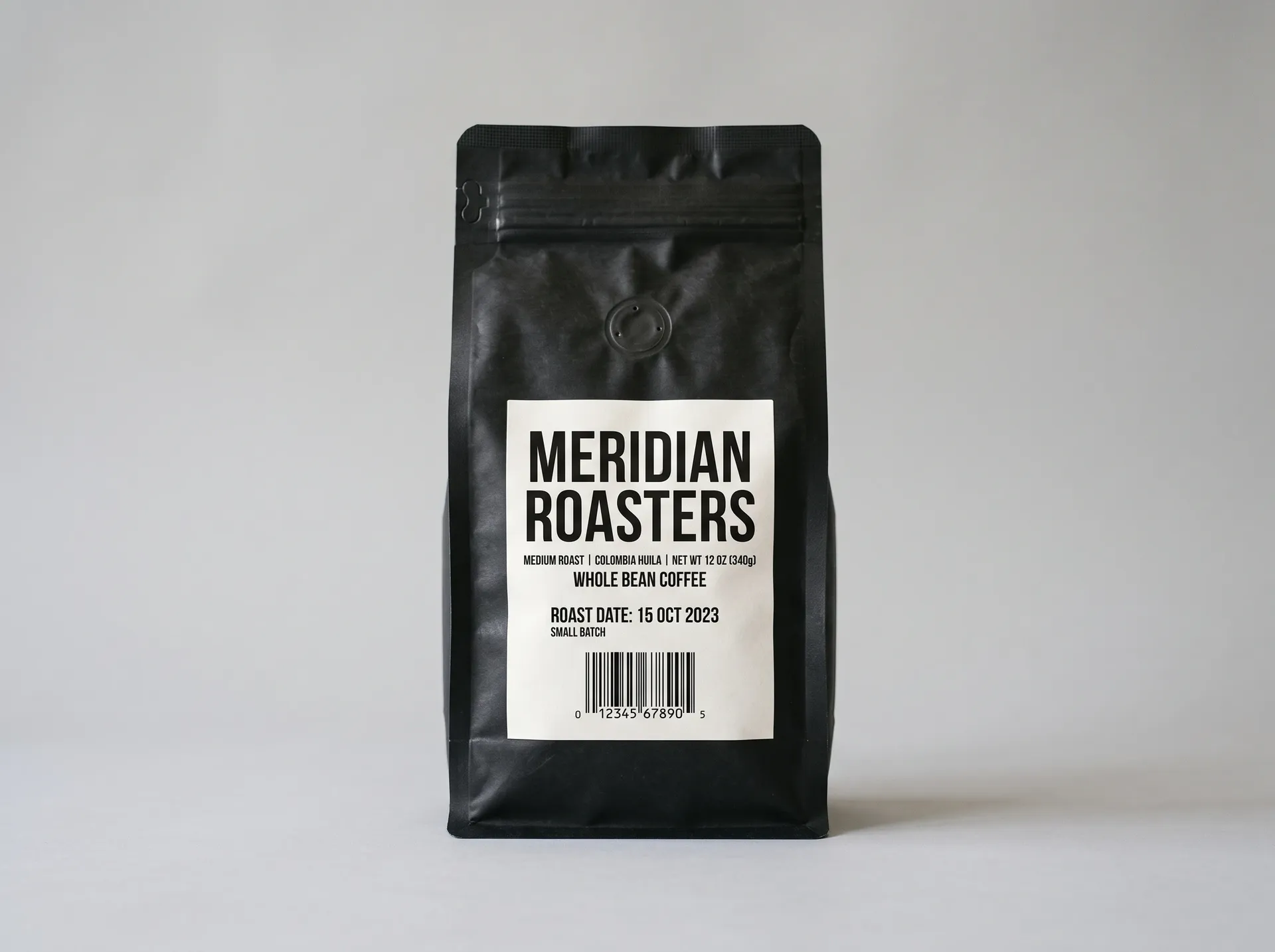 Matte black coffee bag with a printed label on a light gray backdrop, the source photo for the getimg.ai background change test