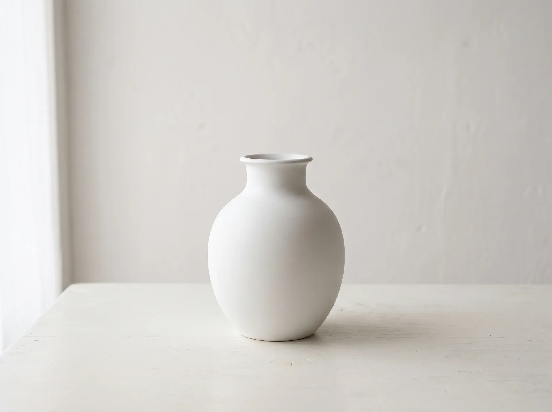White ceramic vase on an off-white table and wall with very low contrast, the source photo for the getimg.ai background change test