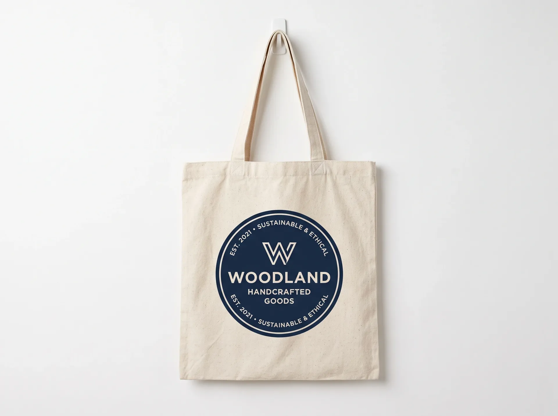 Canvas tote bag with a flat navy circular logo on a white backdrop, the source photo for the getimg.ai background change test