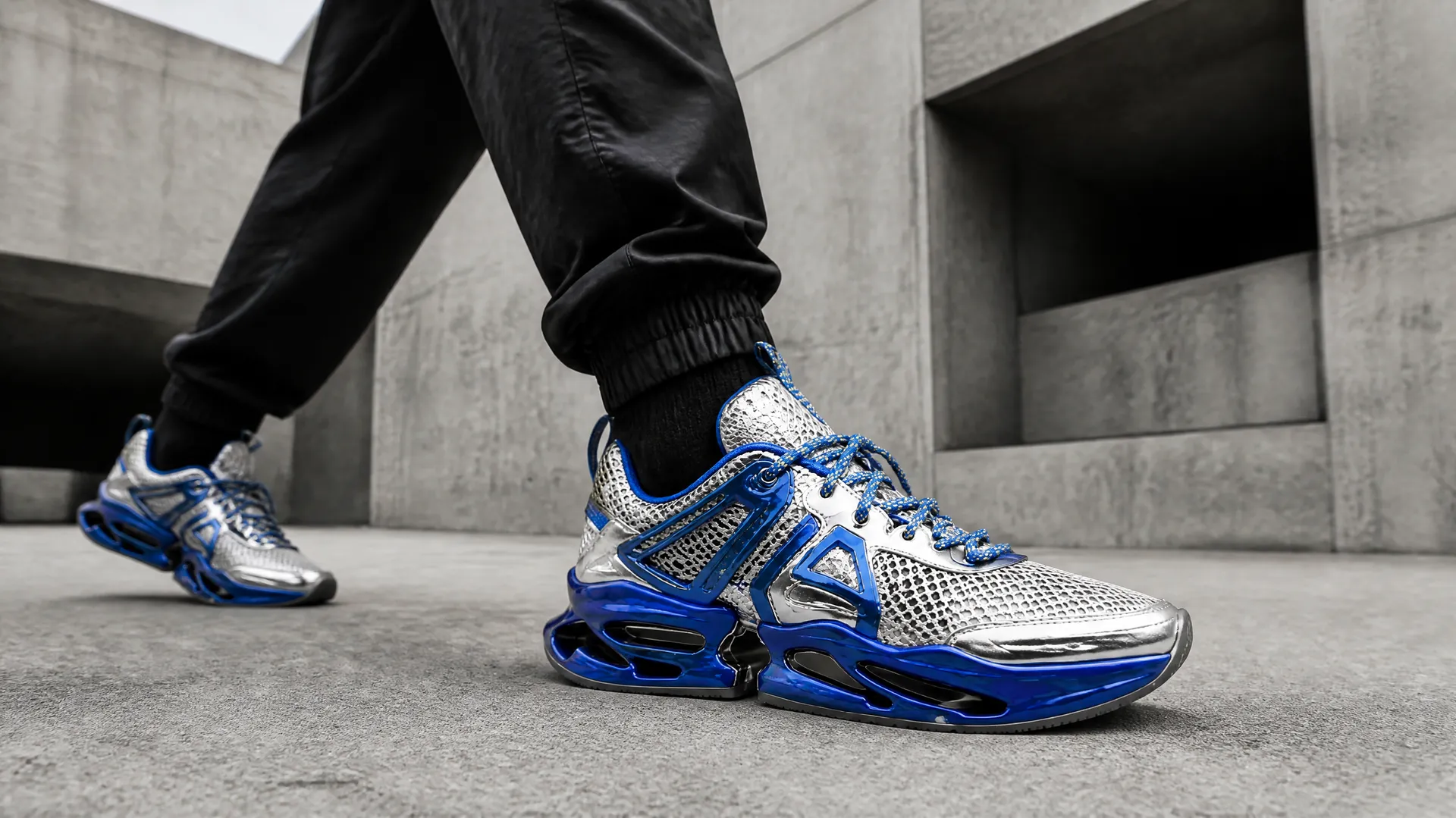 photo of a person wearing futuristic blue, silver, and white sneakers while walking through a brutalist concrete setting, generated with getimg.ai image generator