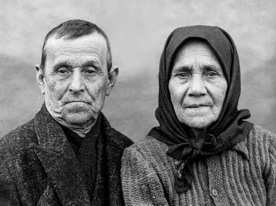 The same portrait of the elderly couple after AI restoration on getimg.ai, with the ink damage removed and facial detail rebuilt, kept in its original black and white.