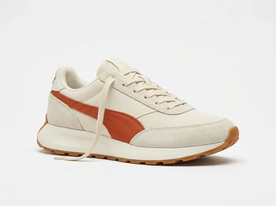 Product photograph of a single off-white running sneaker with a burnt-orange side stripe, suede overlays and a gum sole, isolated on a plain white background under soft even light. Used as the reference image in the reference-guided generation comparison on the getimg.ai Nano Banana 2.1 model page. Generated on getimg.ai with Nano Banana 2.1.