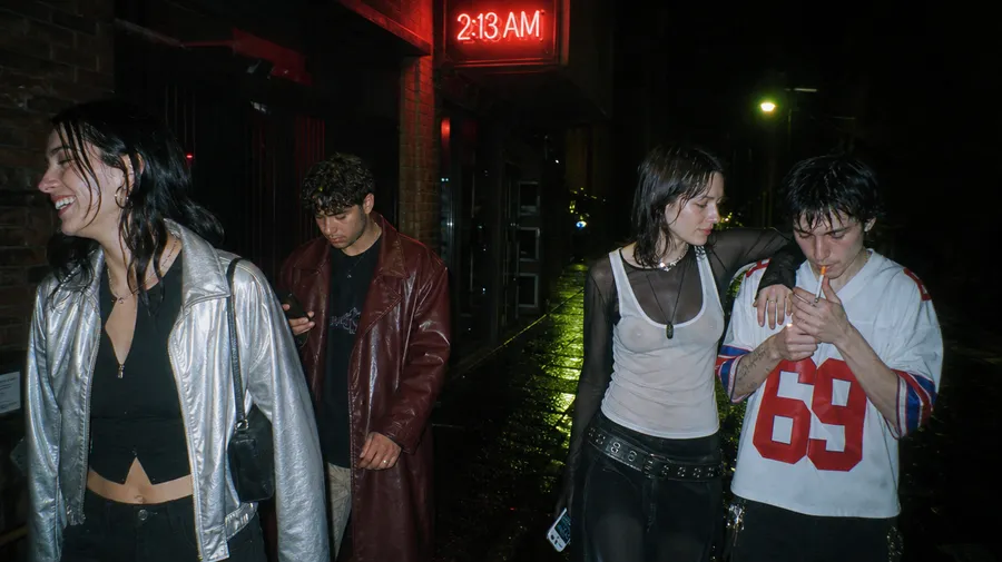 Flash night photo of four friends leaving a club under a red 2:13 AM neon sign in a rain-soaked alley, generated on getimg.ai with GPT Image 2 for an AI image realism test.