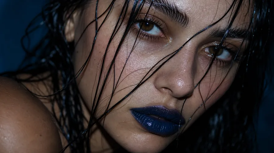 Extreme macro beauty portrait of a young woman with wet dark hair across her face, glossy dark-blue lips and freckled skin under hard flash, generated on getimg.ai with GPT Image 2 for an AI image realism test.