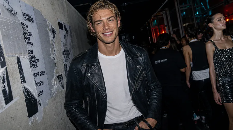 Backstage fashion-show photo recreating the reference man in a leather jacket with wet-look hair, testing identity preservation, generated on getimg.ai with GPT Image 2 for an AI image realism test.