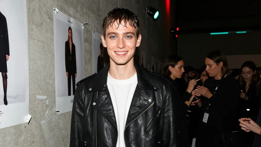 Backstage fashion-show photo recreating the reference man in a leather jacket with wet-look hair, testing identity preservation, generated on getimg.ai with Z-Image Turbo for an AI image realism test.