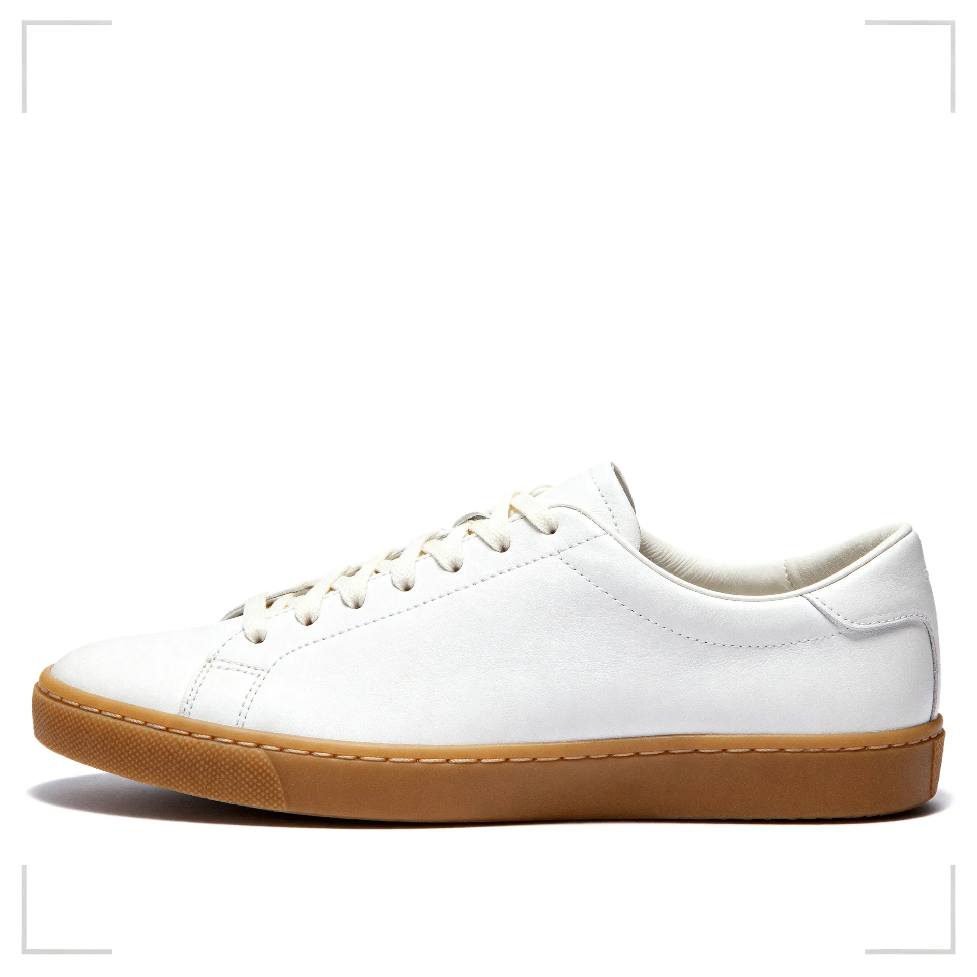 White leather low-top sneaker with a gum rubber sole and tonal laces, side view on a pure white background. Studio packshot generated in getimg.ai.
