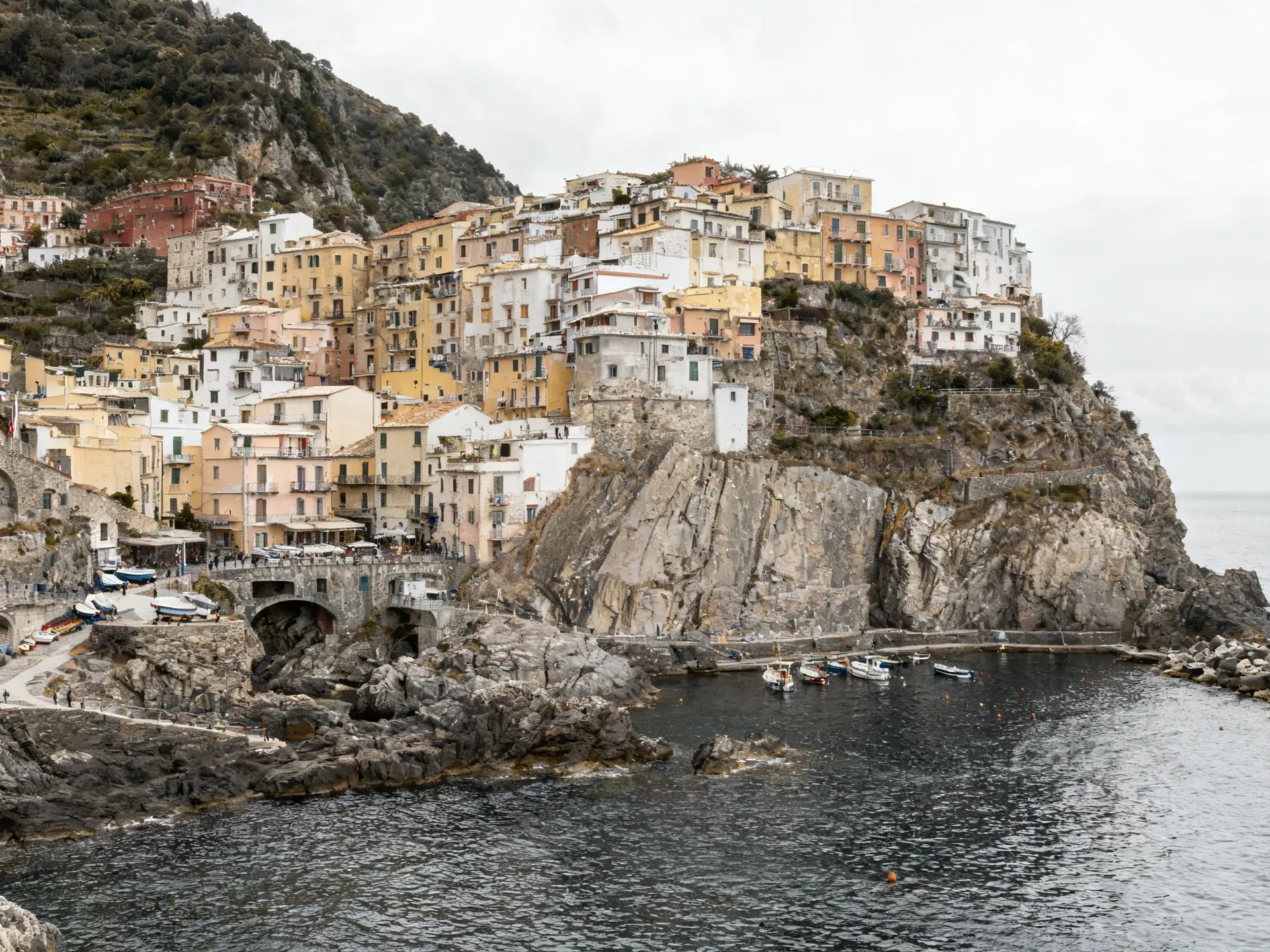 Mediterranean hillside town of pastel houses above a small fishing harbour, photographed in flat overcast midday light. Source photo for getimg.ai's time-of-day editing test, generated with getimg.ai.