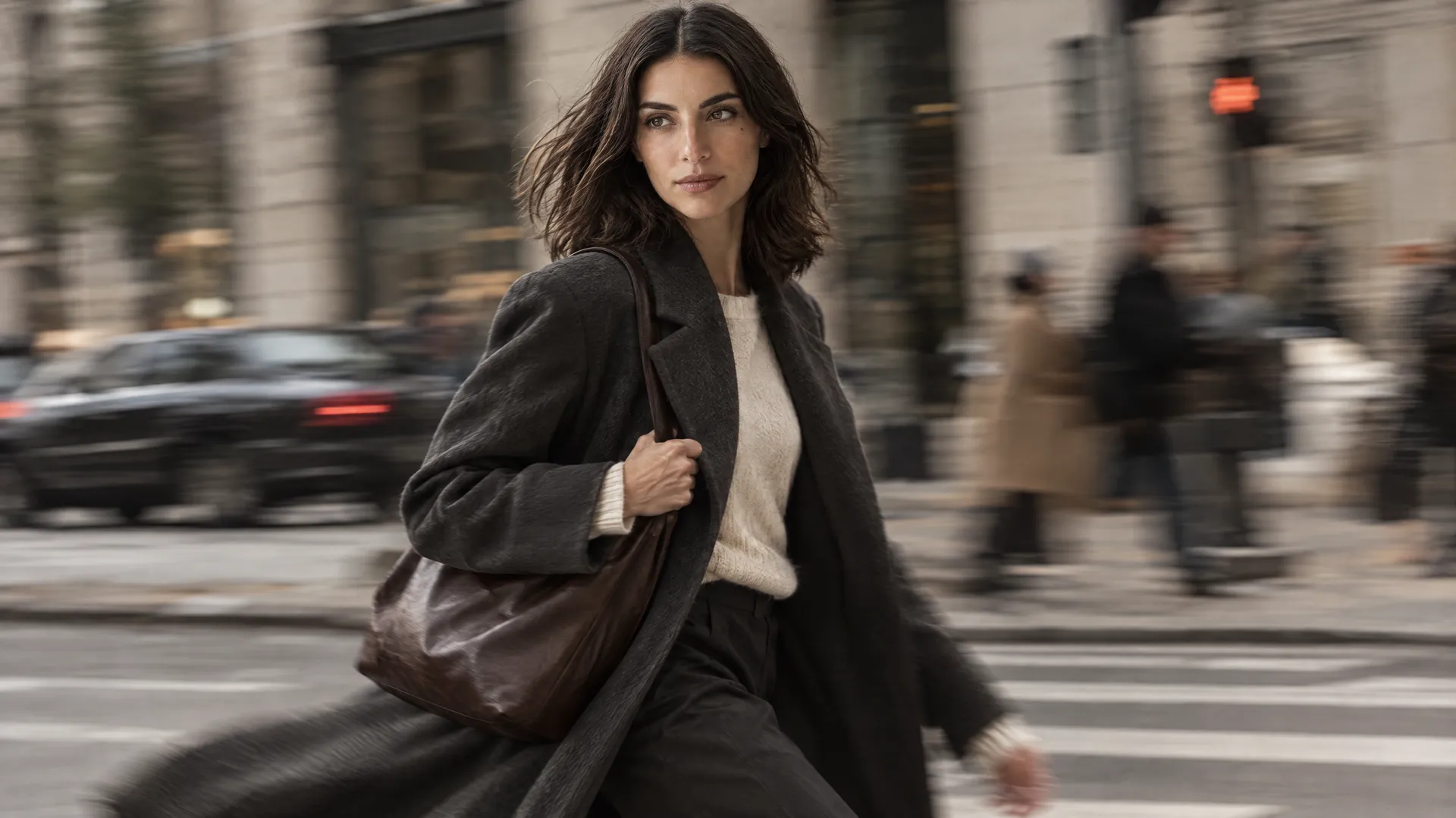 An AI-generated motion shot of Mara in a dark coat striding across a city crosswalk with the background blurred, the Round 5 movement test; created on getimg.ai.