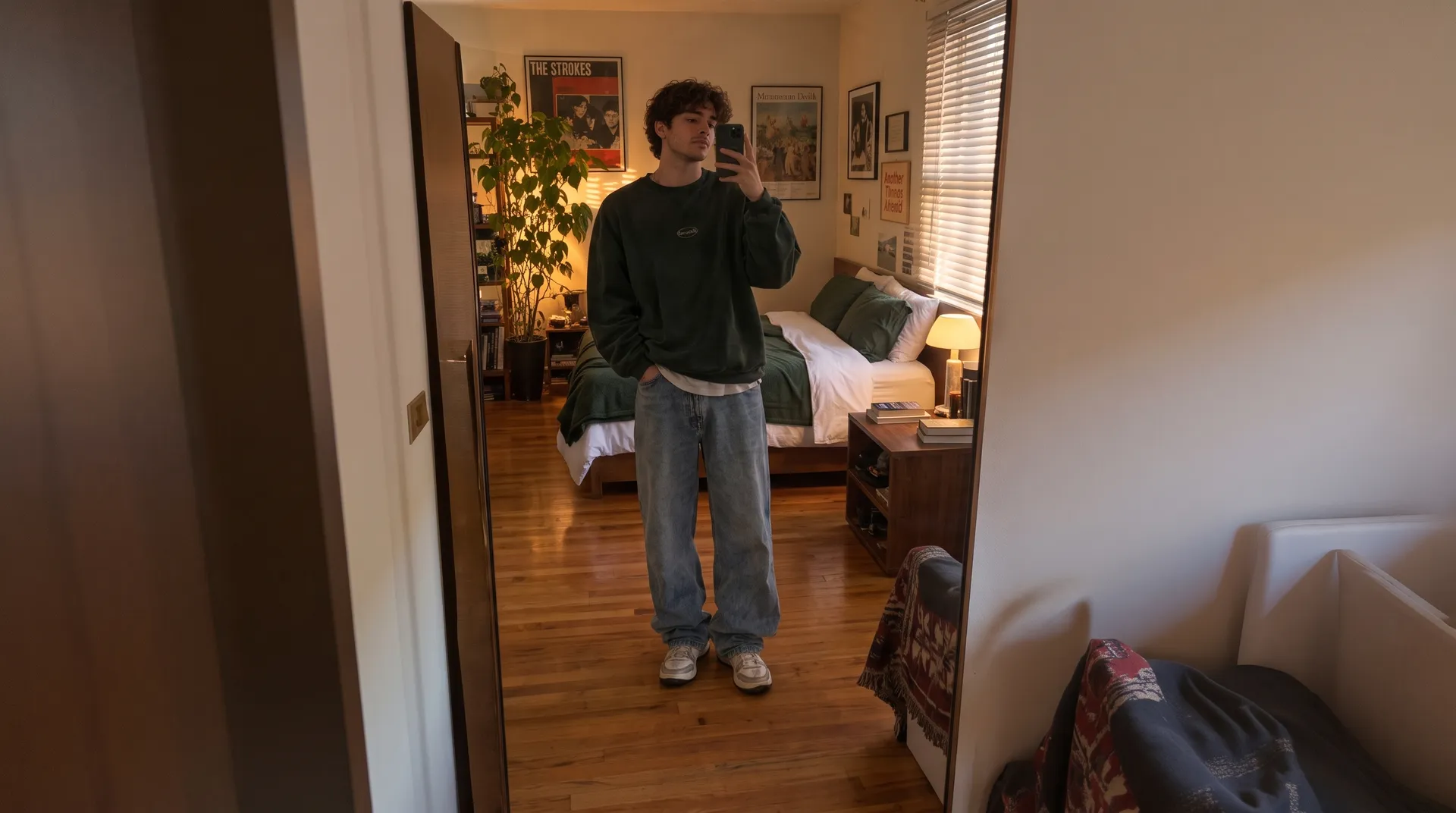After AI object removal on getimg.ai: the same mirror selfie of the young man, with the scattered clothes, laundry basket and clutter removed and the clean wooden floor and tidy, made bed rebuilt behind him.
